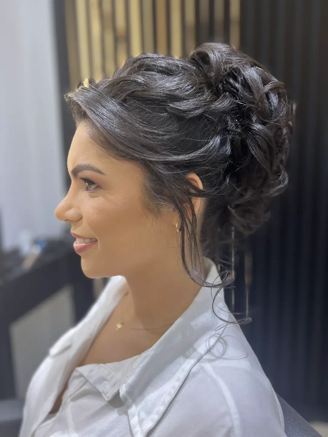 Penteado coque volumoso, cliente sorrindo de perfil