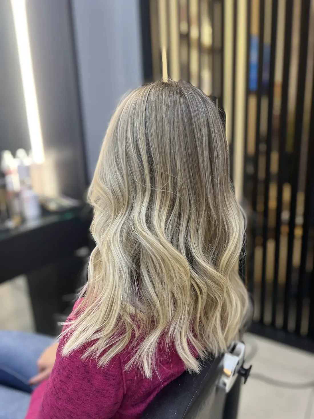 Cliente com mechas loiras iluminadas em cadeira de salão