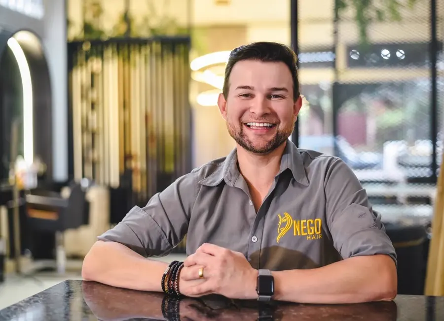 Ederson Garcia, fundador do Nego Hair, sorrindo no salão